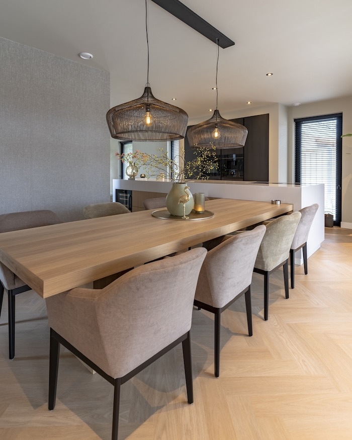 Moderne eetkamer met decoratief servies, bloemenvaas en sfeervolle verlichting boven tafel