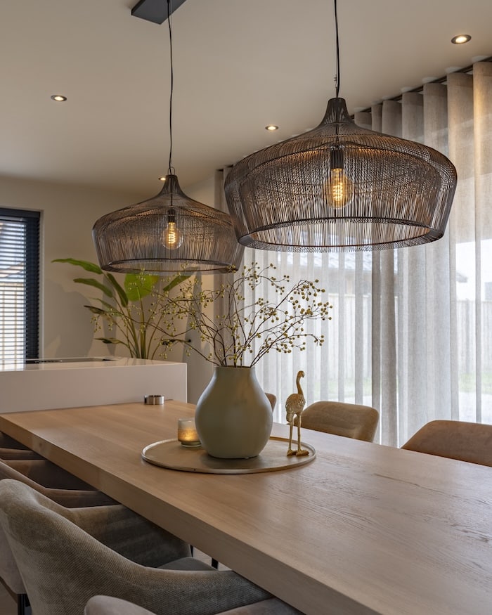 Tafelstyling met matte vaas, kaarslicht en goudkleurige accessoires onder zwarte lampen