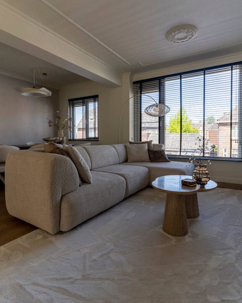 Interieurfoto van een warme woonkamer met een zachte, lichtbruine bank en houten salontafel in een appartement in Enschede