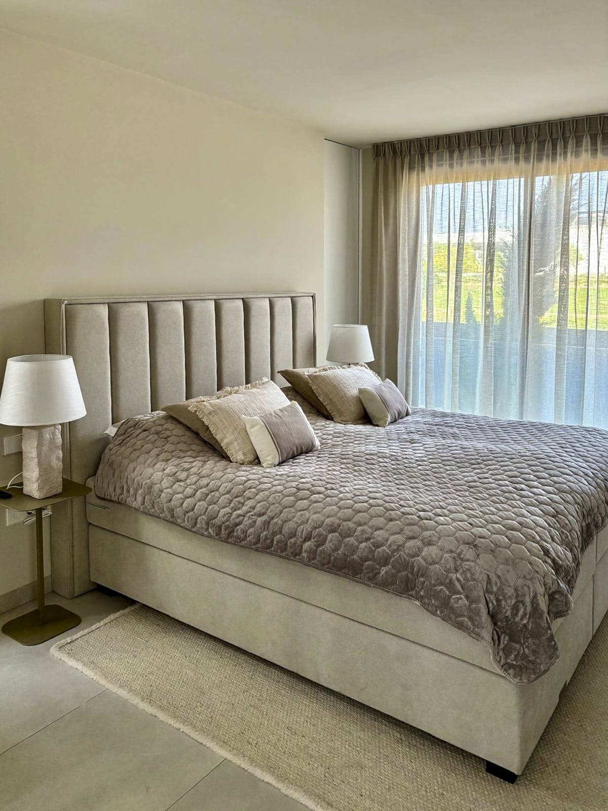 Luxe boxspring in neutrale kleuren met bijpassende nachtkastjes en sfeervolle verlichting.