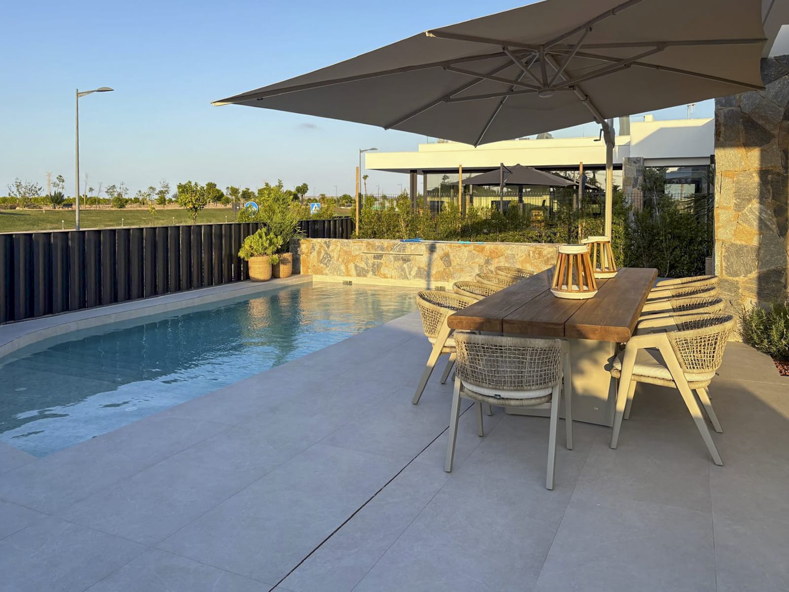 Gezellig terras met natuurlijke materialen, grote parasol en sfeervolle verlichting