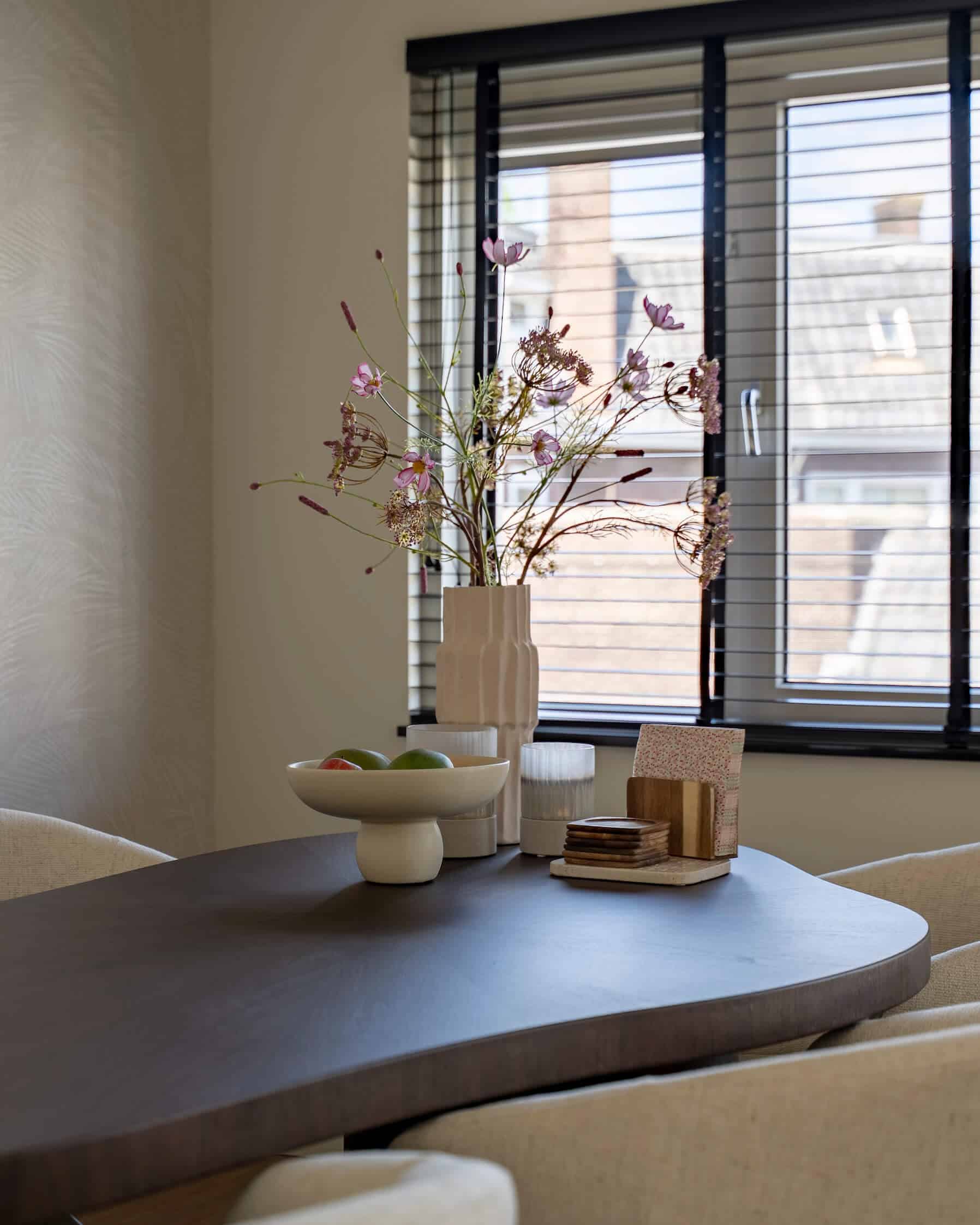 Close-up van tafeldecoratie met vaas, fruit en onderzetters bij het raam in een warme eetkamer