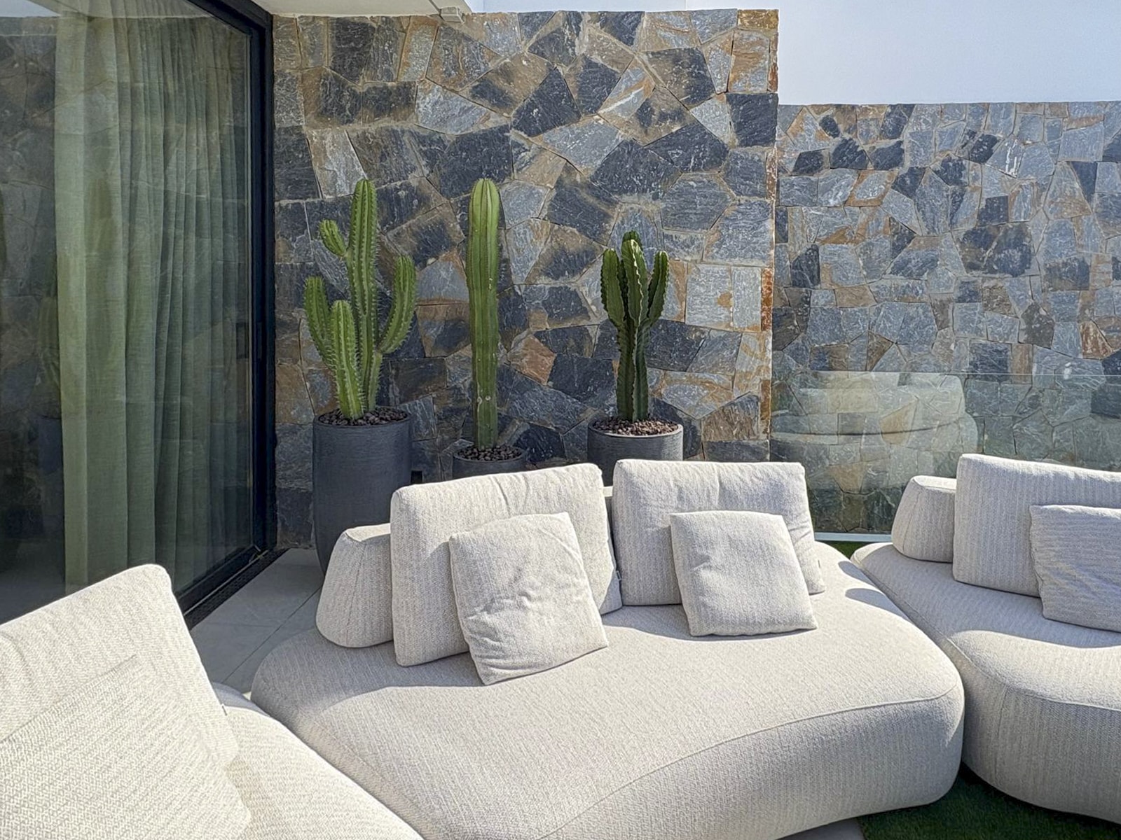 Organische loungebank in buitenruimte met rotspartij, cactussen en strak grasveld