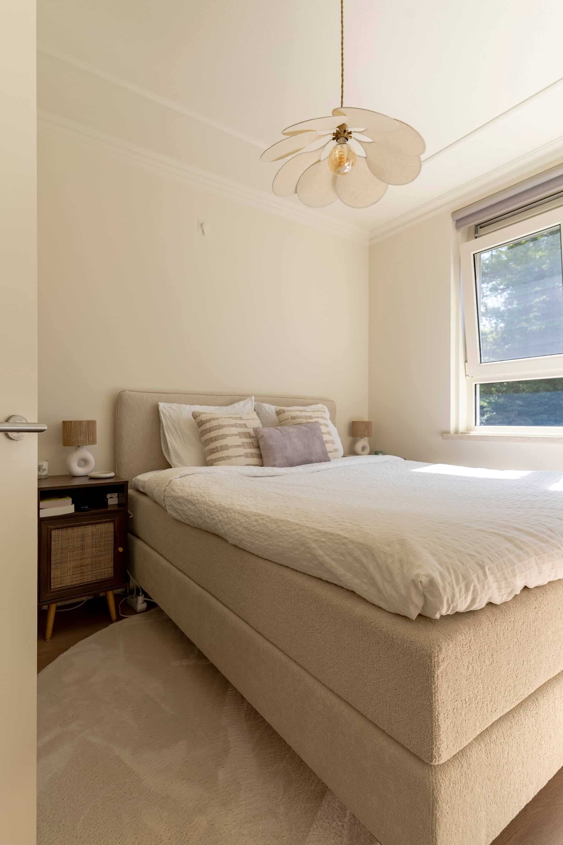 Zijkant van het bed met bijpassend nachtkastje en accessoires in natuurlijke materialen