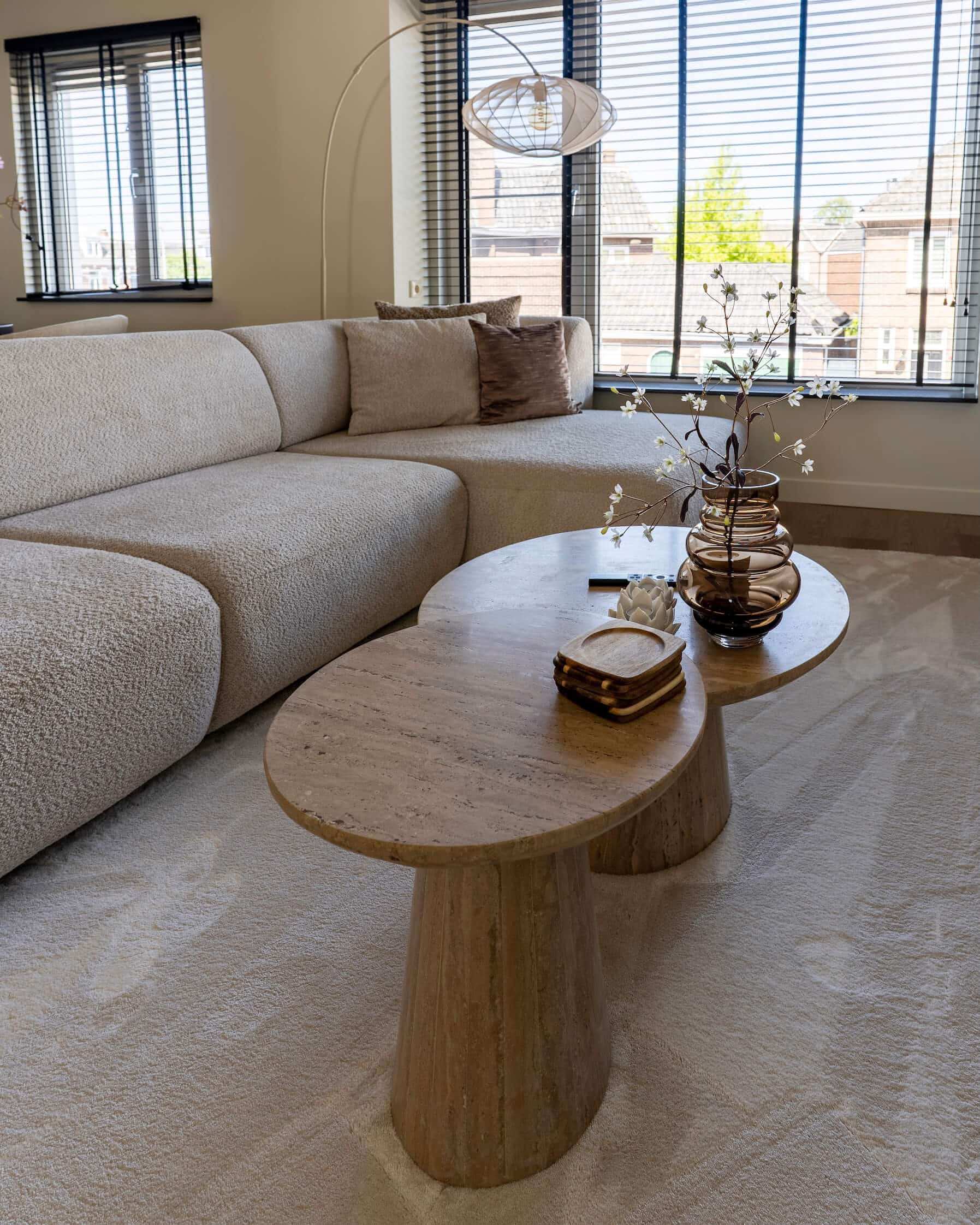 Ovale salontafels van travertin en een zachte bank vormen het hart van deze gezellige woonkamer