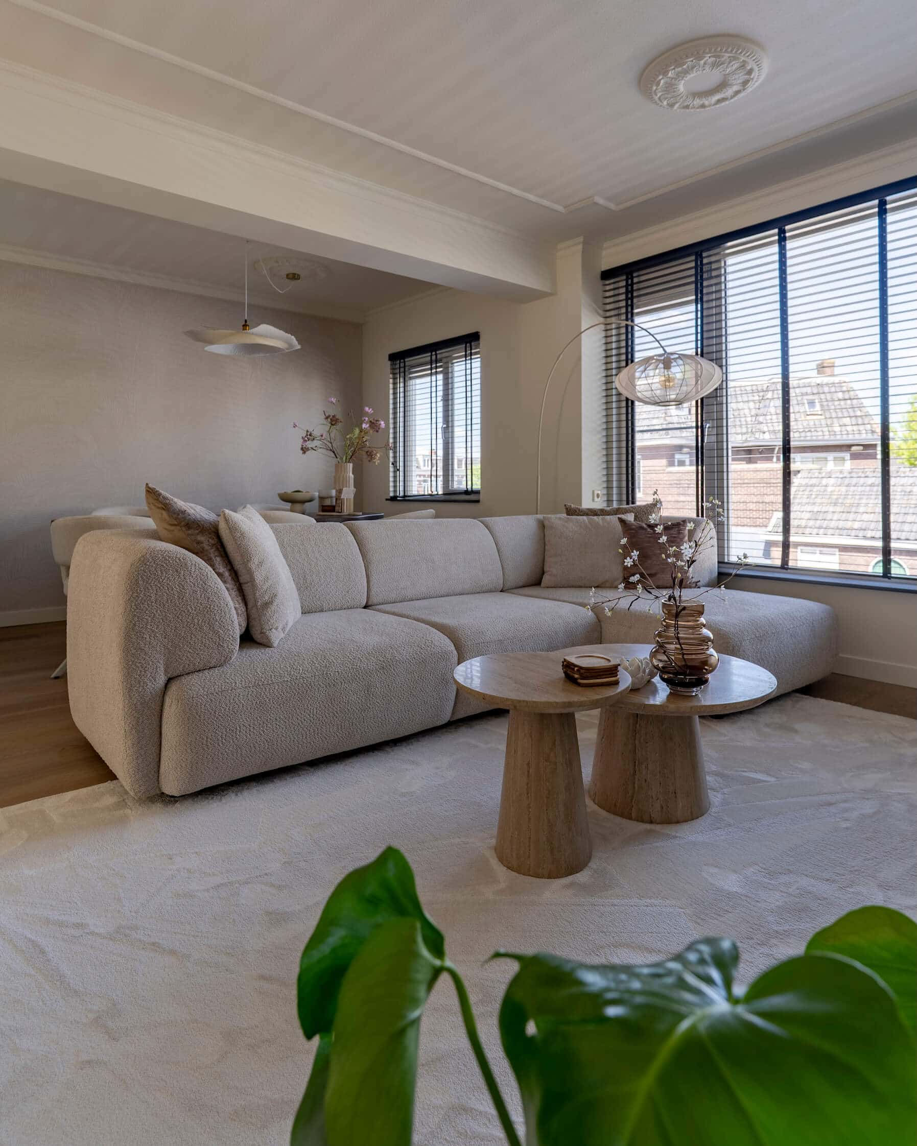 Interieurbeeld met zachte bank, styling op tafel en stijlvolle raamdecoratie in modern appartement