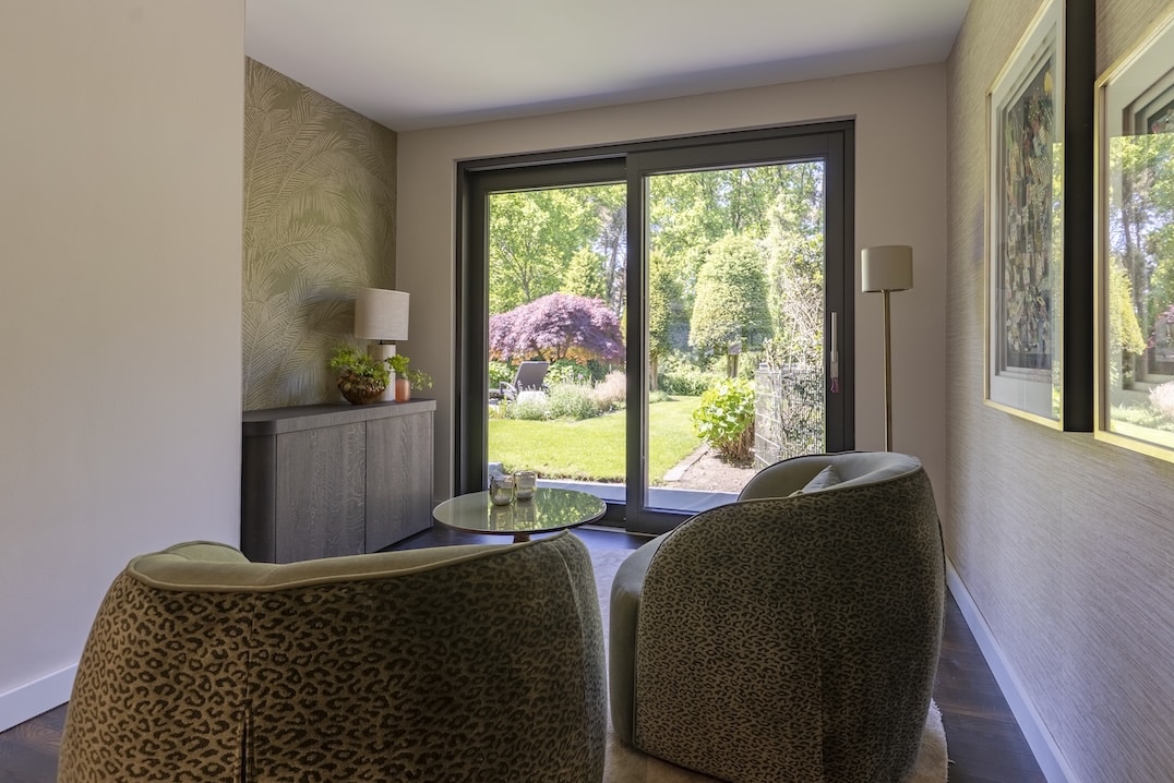Doorkijk naar kleurrijke tuin vanuit zithoek met twee ronde fauteuils