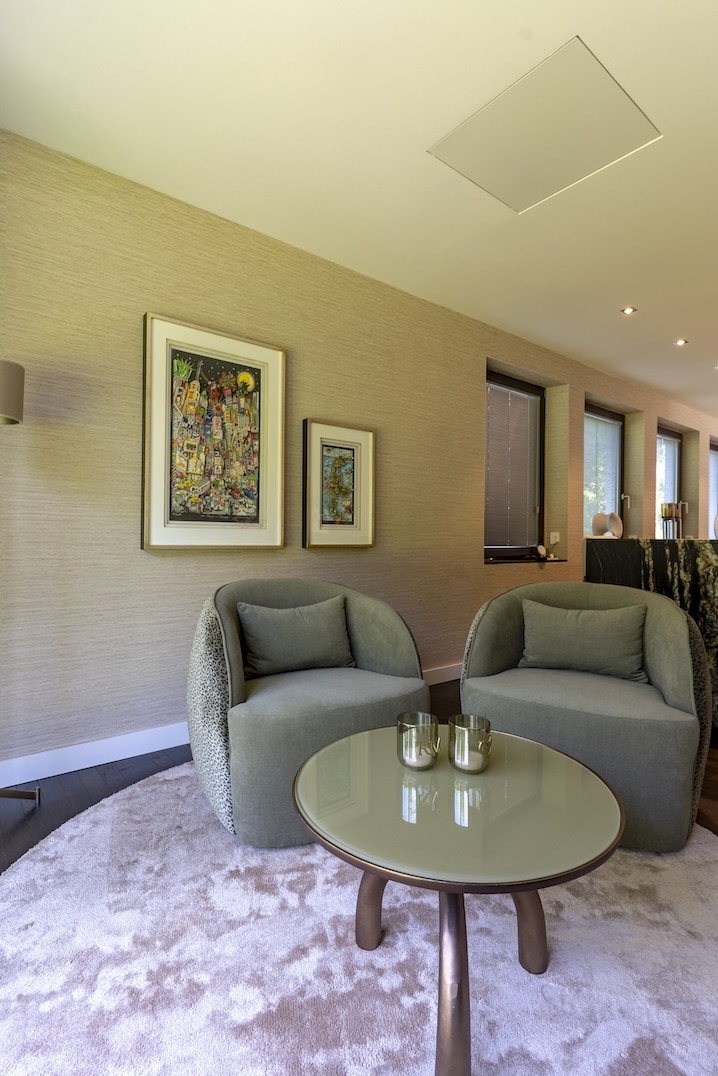 Twee moderne fauteuils met ronde glazen salontafel en sfeervolle verlichting