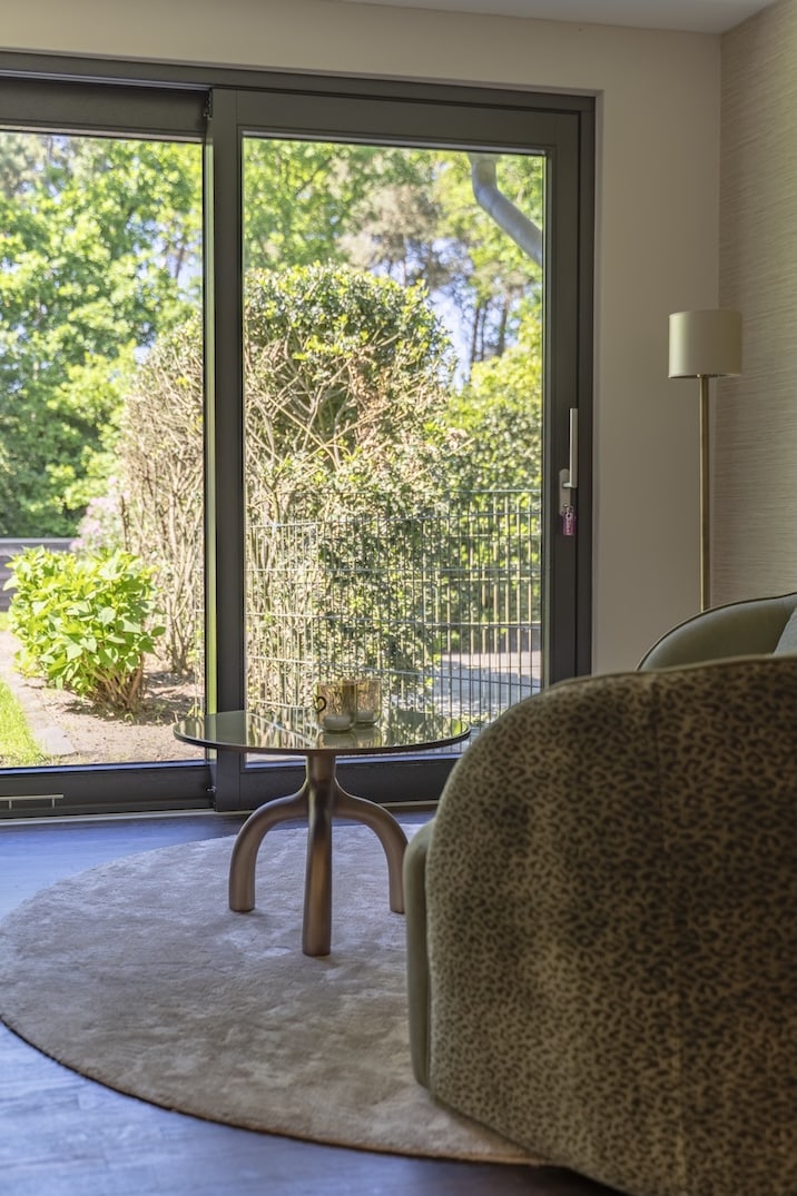 Zithoek met uitzicht op groene tuin en zachte ronde vloerkleed