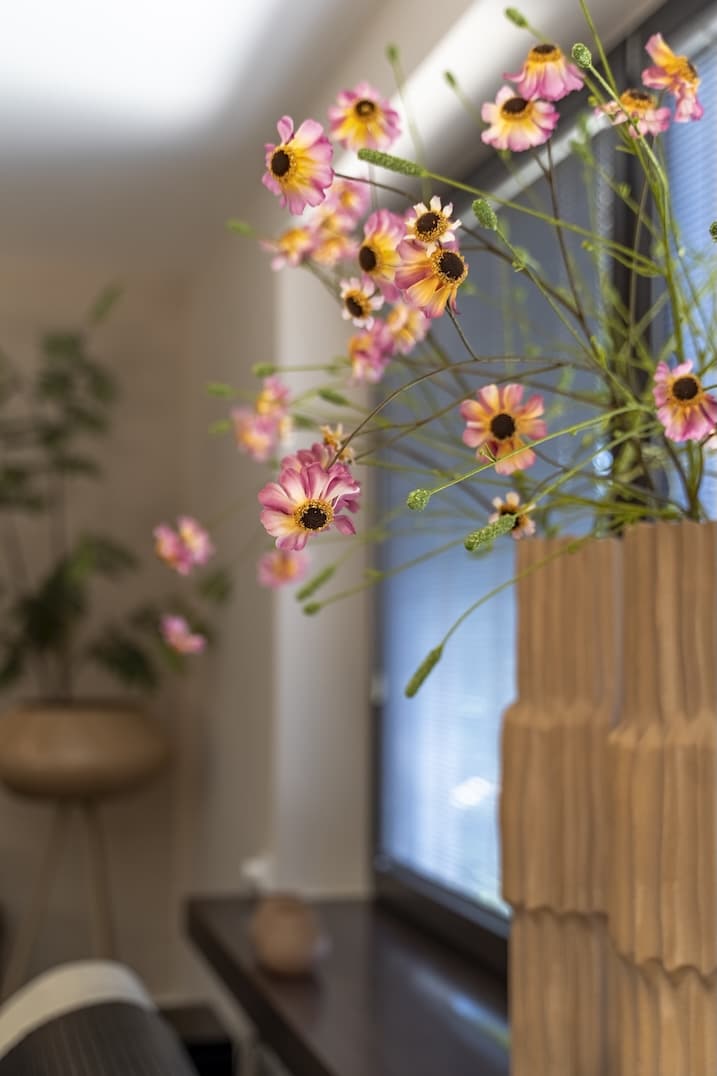 Detailopname van roze bloemen in een grafische vaas met lichtinval van opzij