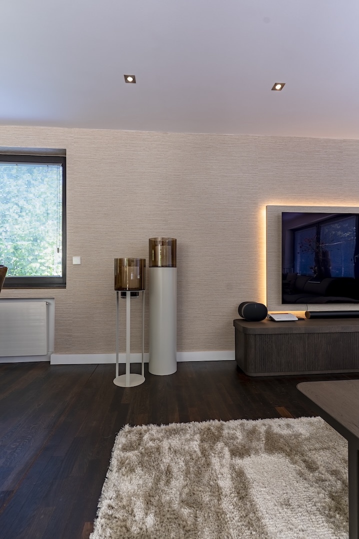 Close-up van groot televisiescherm op een donker houten meubel met sfeerverlichting in modern interieur