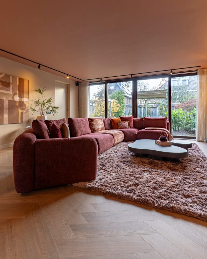 Kleurrijk interieur van vrijstaande woning in Enschede met royale bordeauxrode hoekbank