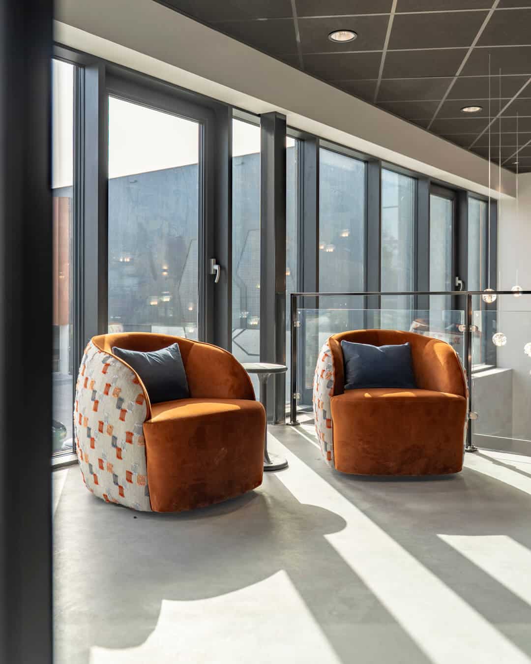 Twee compacte fauteuils met patroon en warme kussens in lichte kantoorruimte