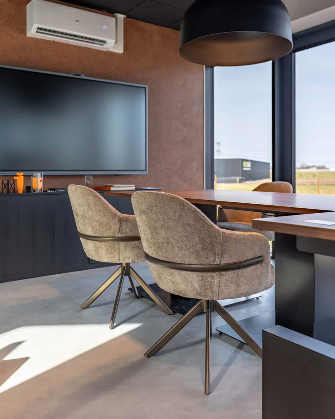 Vergadertafel met gestoffeerde stoelen en maatwerk wandmeubel in kantoorinterieur