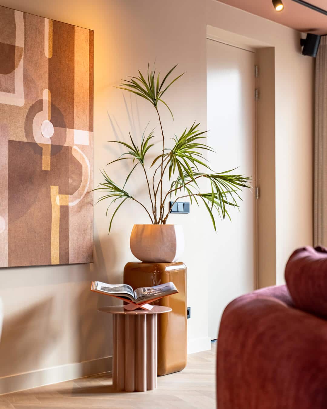 Interieurstyling met plant, design bijzettafel en kunstwerk in warme kleuren