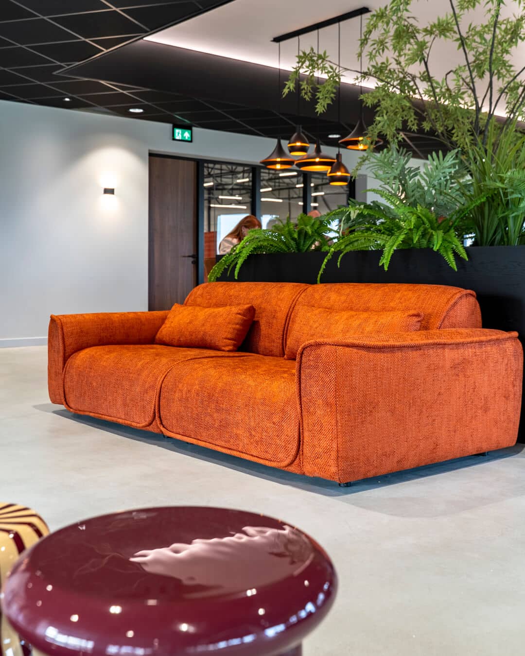 Oranje loungebank met groene plantenwand in moderne werkomgeving