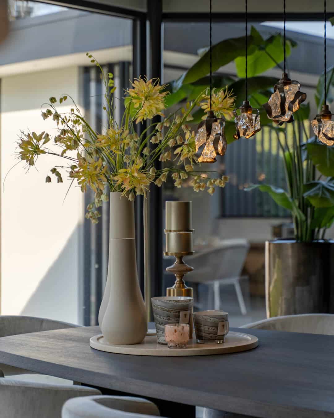Styling op de eettafel met hoge vazen, bloemen en decoratieve accessoires