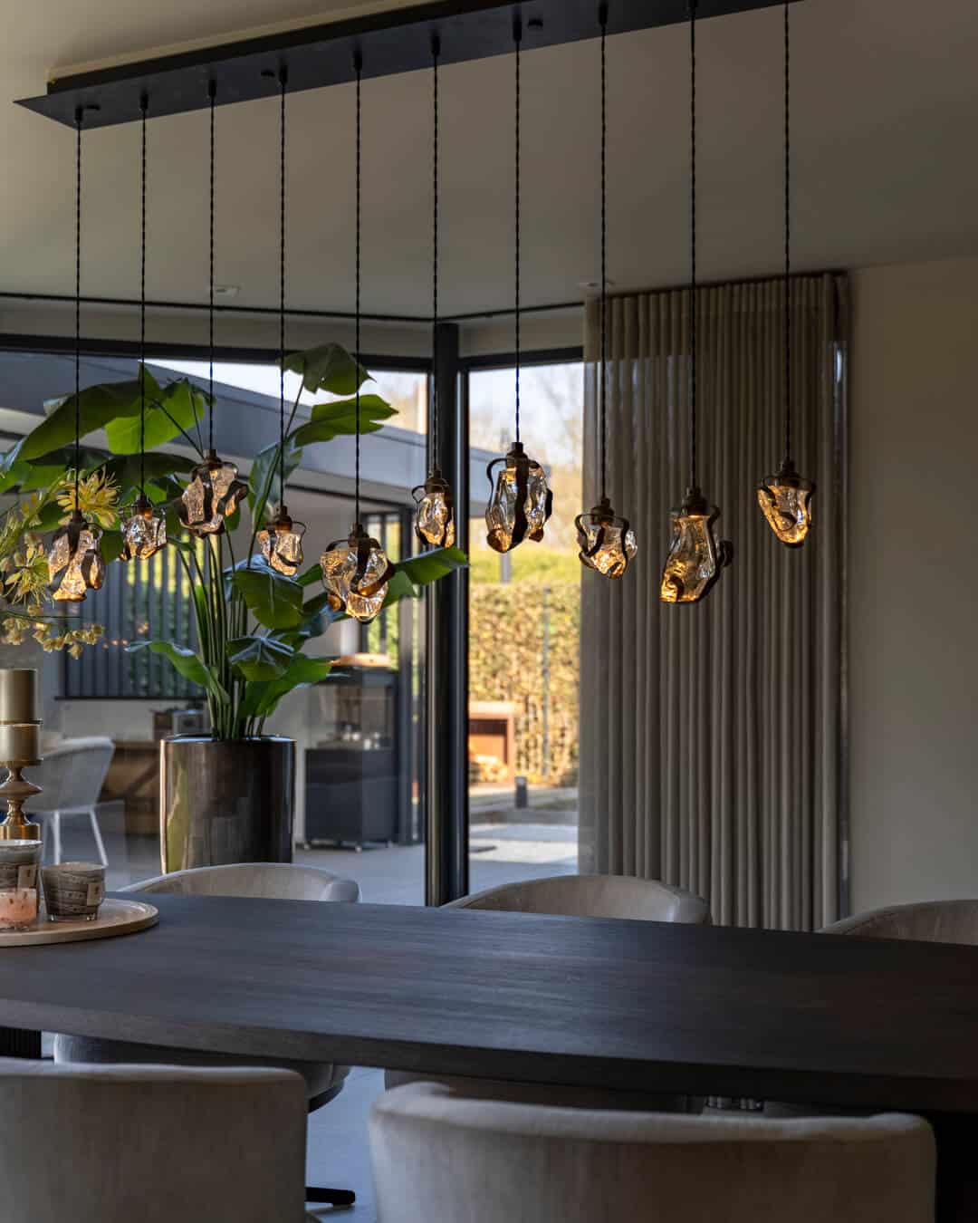 Bijzondere hanglamp boven luxe eettafel met uitzicht op de tuin