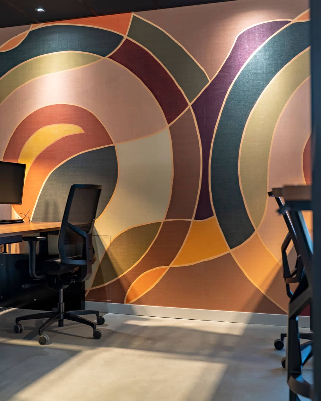 Werkplek met kleurrijk grafisch wanddesign in modern kantoorinterieur