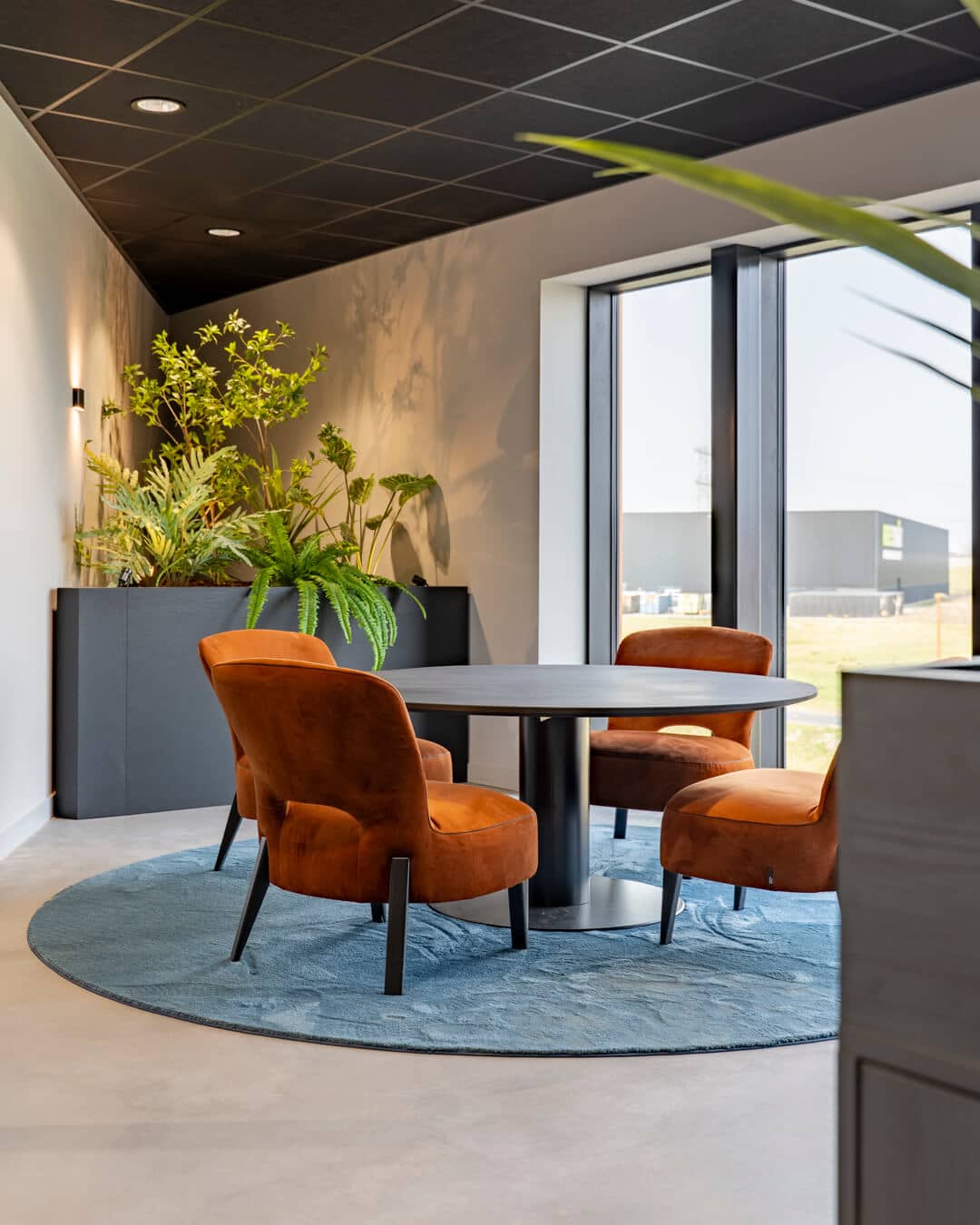 Informele overlegplek met ronde tafel, fauteuils en veel groen