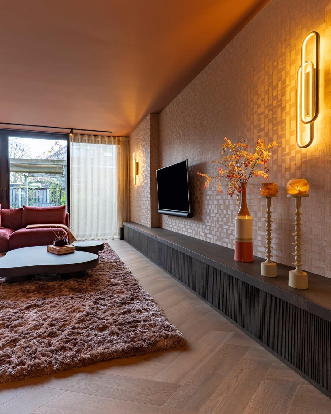 Luxe woonkamer met maatwerk tv-meubel, sfeerverlichting en warm behang