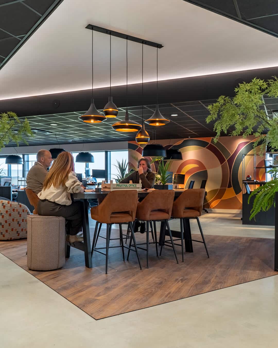 Moderne ontmoetingsruimte met hoge tafel, barkrukken en opvallende wanddecoratie
