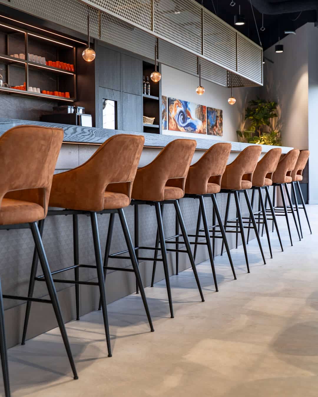 Hoge bar met gestoffeerde barkrukken en maatwerk kastenwand in bedrijfspand