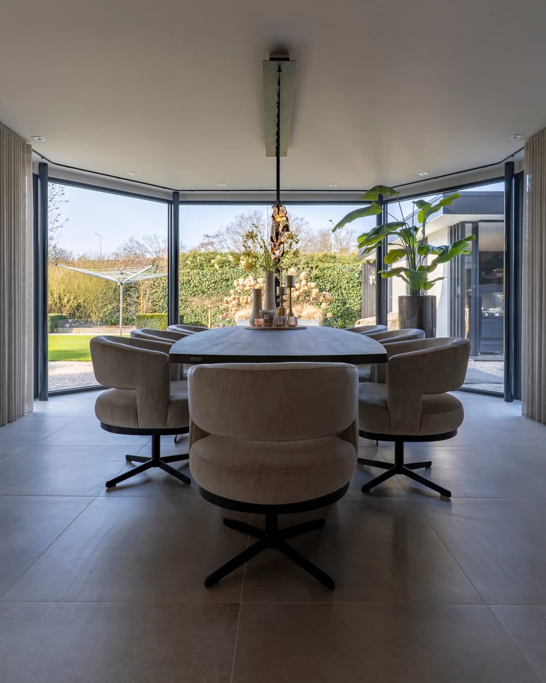 Lichte eetkamer met grote eettafel, comfortabele stoelen en uitzicht op de tuin