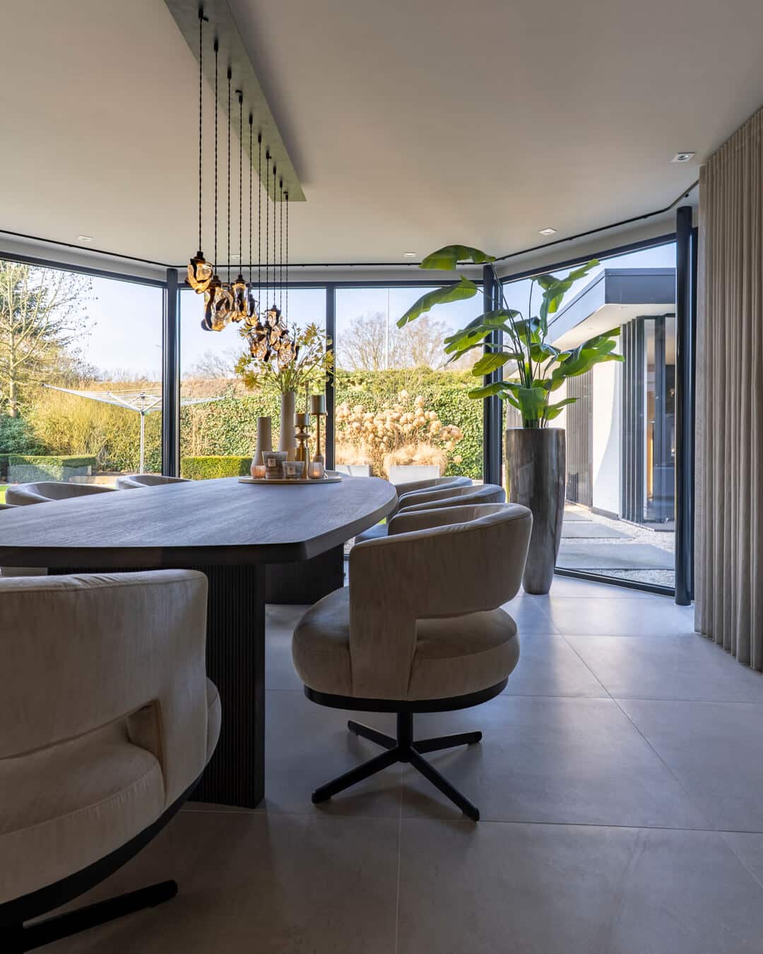 Moderne eetkamer in rustige aardetinten met zicht op de groene tuin