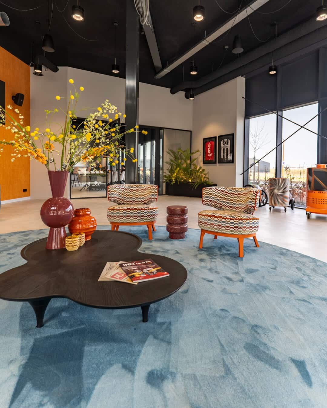 Moderne kantoorlounge met organische salontafels, fauteuils en kleurrijke accessoires
