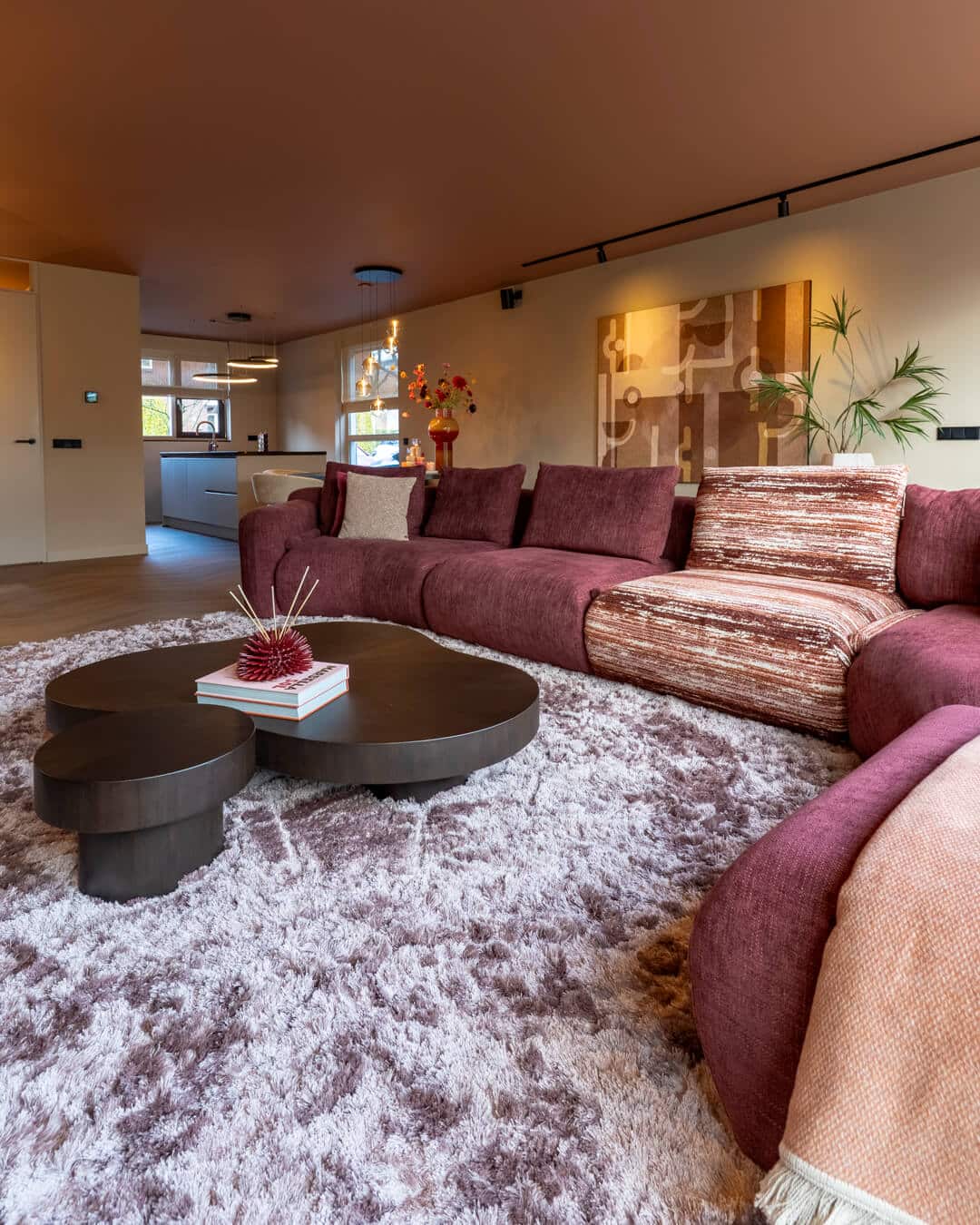 Luxe woonkamer met organische salontafel, hoogpolig vloerkleed en kleurrijke bank