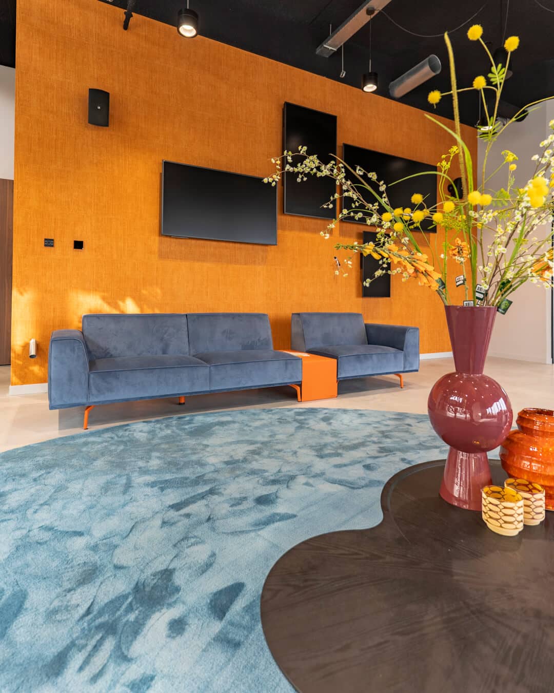Blauwe loungebank tegen warme oranje accentwand in modern bedrijfspand