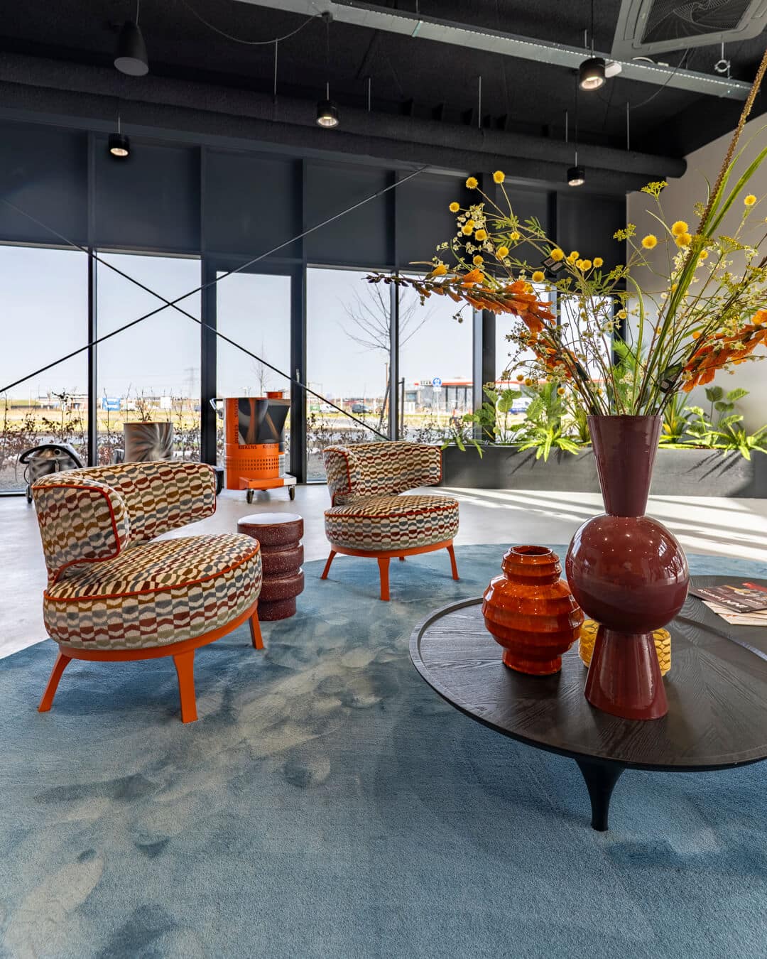 Sfeervolle lounge met designfauteuils, groot vloerkleed en kleurrijke styling
