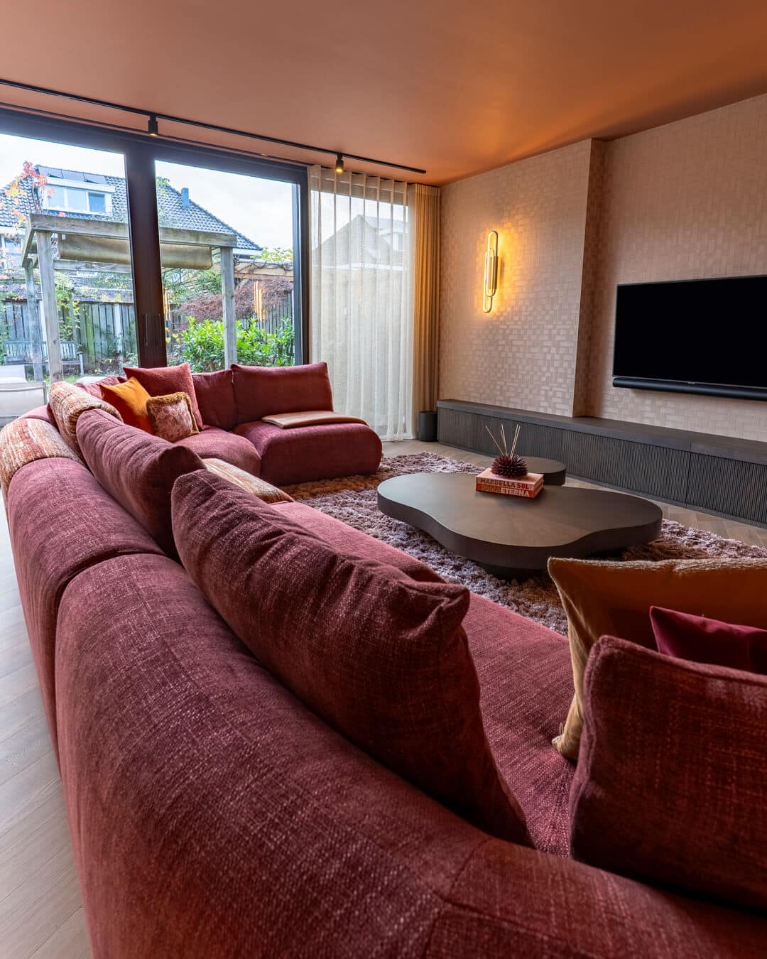 Luxe woonkamer met grote hoekbank, organische salontafel en maatwerk interieur