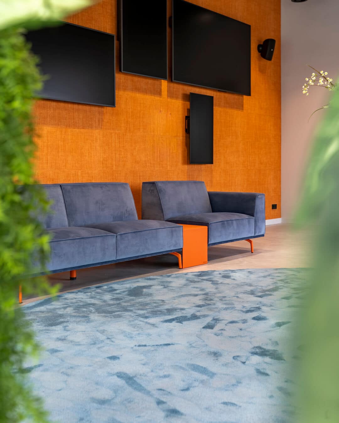 Blauwe loungebank en oranje bijzettafel in kleurrijk kantoorinterieur in Hengelo