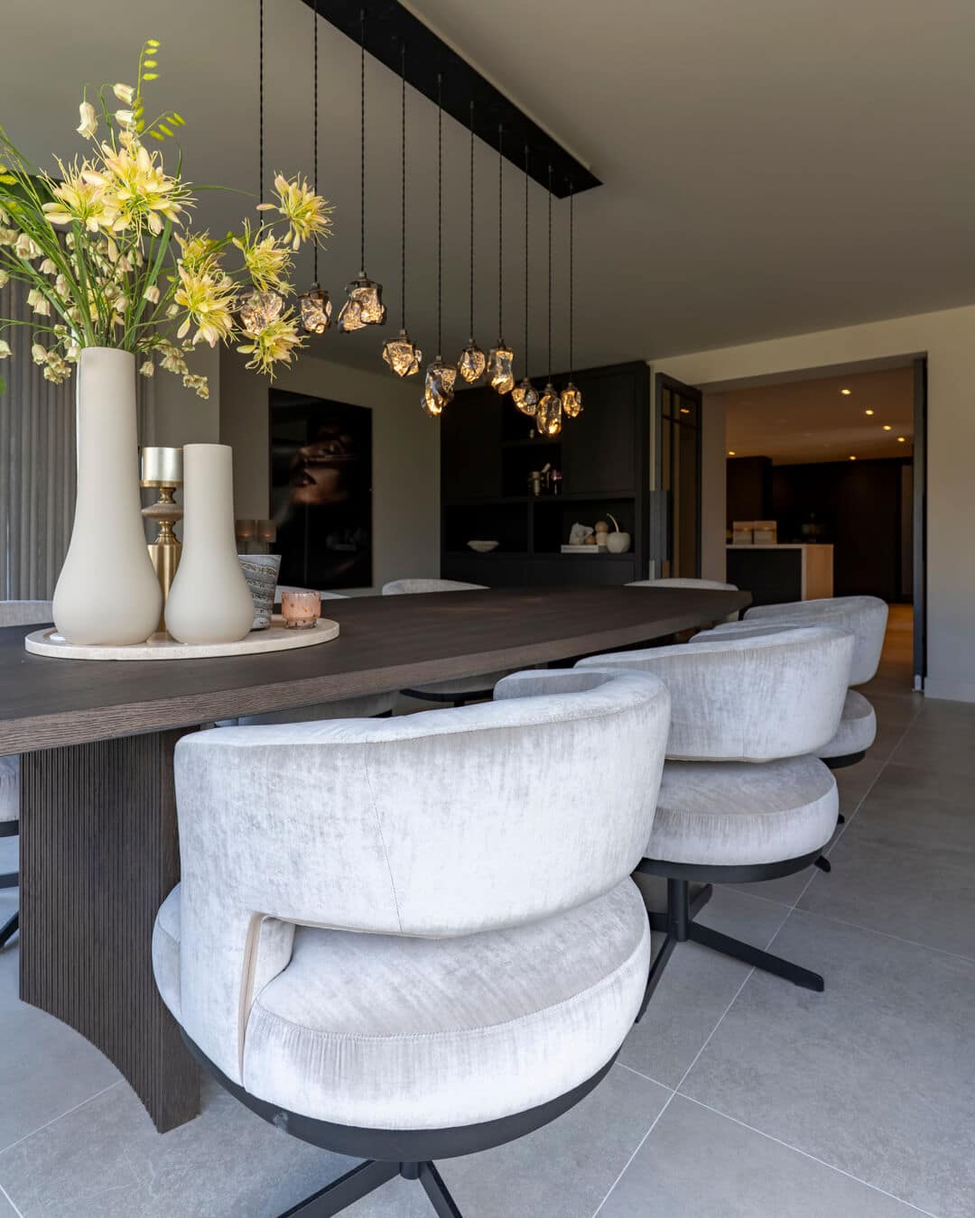 Detail van luxe eettafel met decoratieve vazen en gestoffeerde eetkamerstoelen