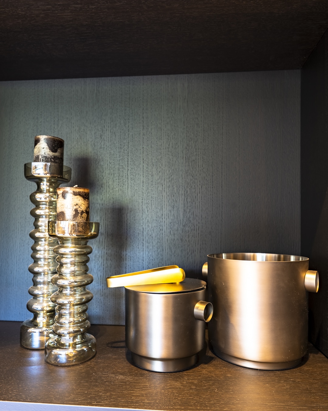 Decoratieve metalen accessoires in open vak van de donkere maatwerkkast.