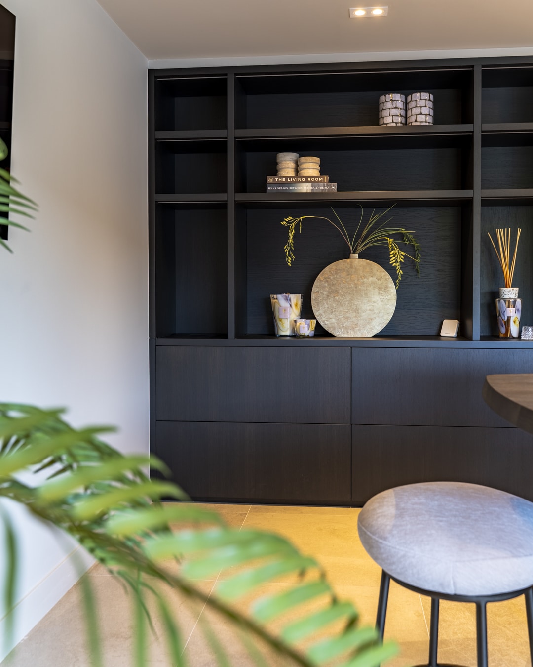 Donkere maatwerkkast met luxe accessoires en organische decoratie.