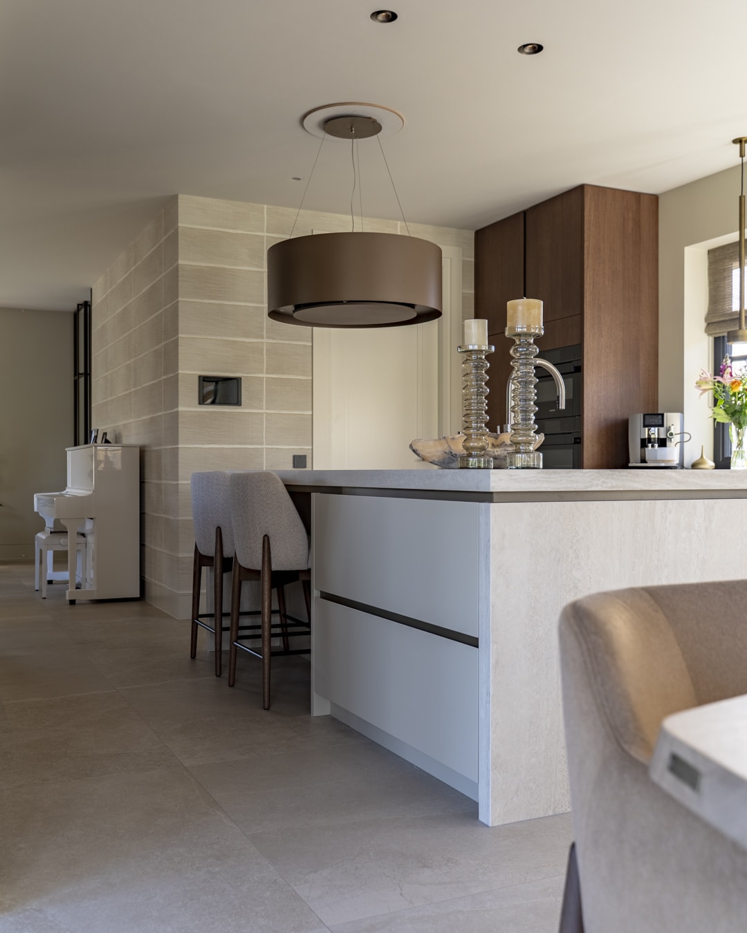 Luxe open keuken met kookeiland en warme houten kasten in een nieuwbouwvilla.