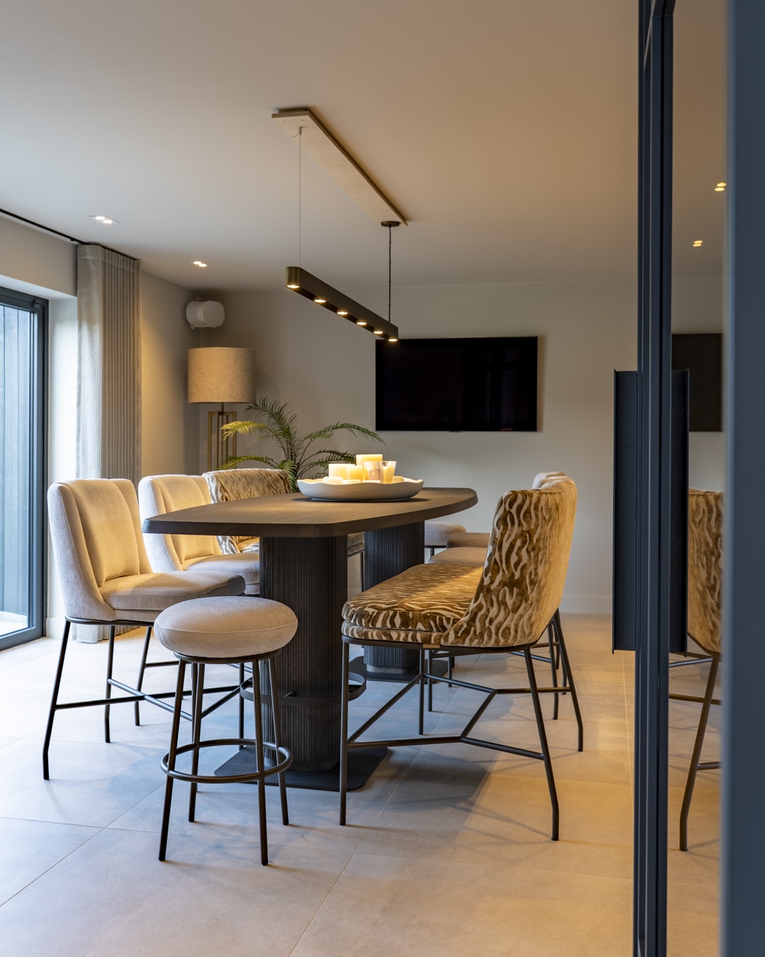 Moderne bar aan huis met veel daglicht, warme stoffen en donkere interieuraccenten.