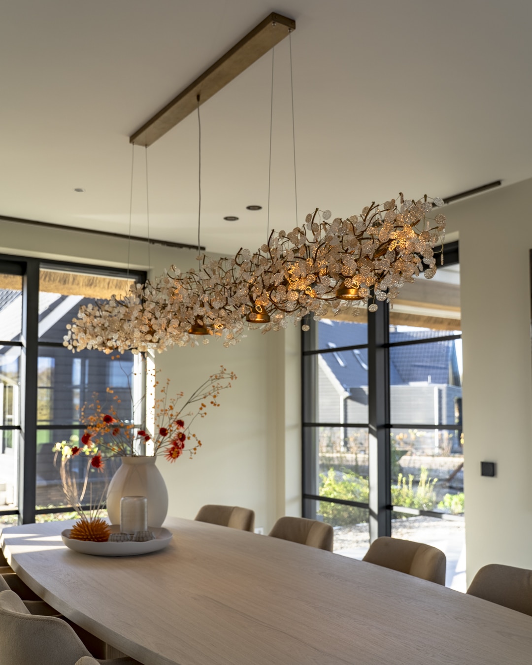 Sculpturale designverlichting boven een ovale eettafel in een modern interieur.