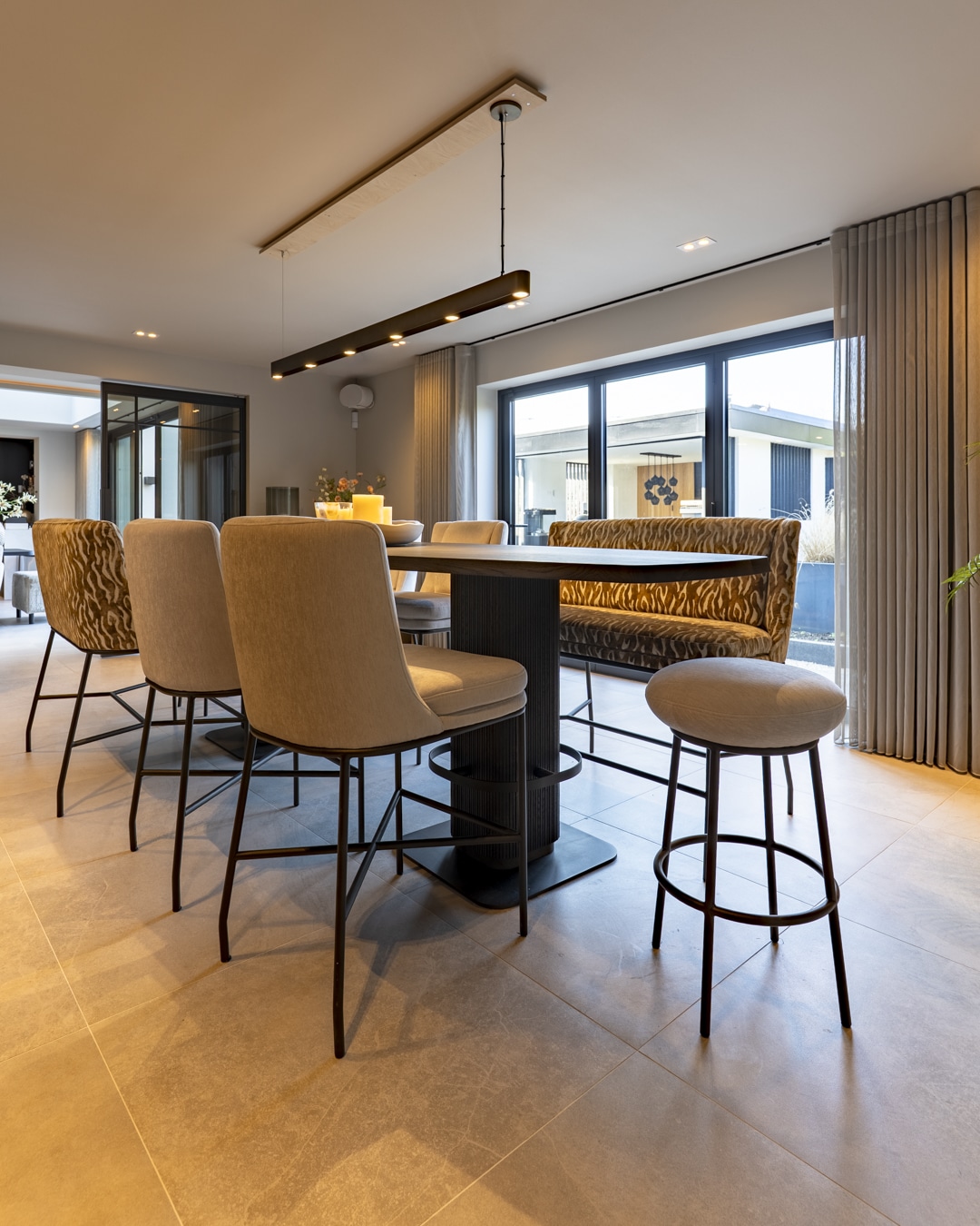 Sfeervolle bar aan huis met ronde bartafel, zachte eetkamerstoelen en opvallende fauteuils.
