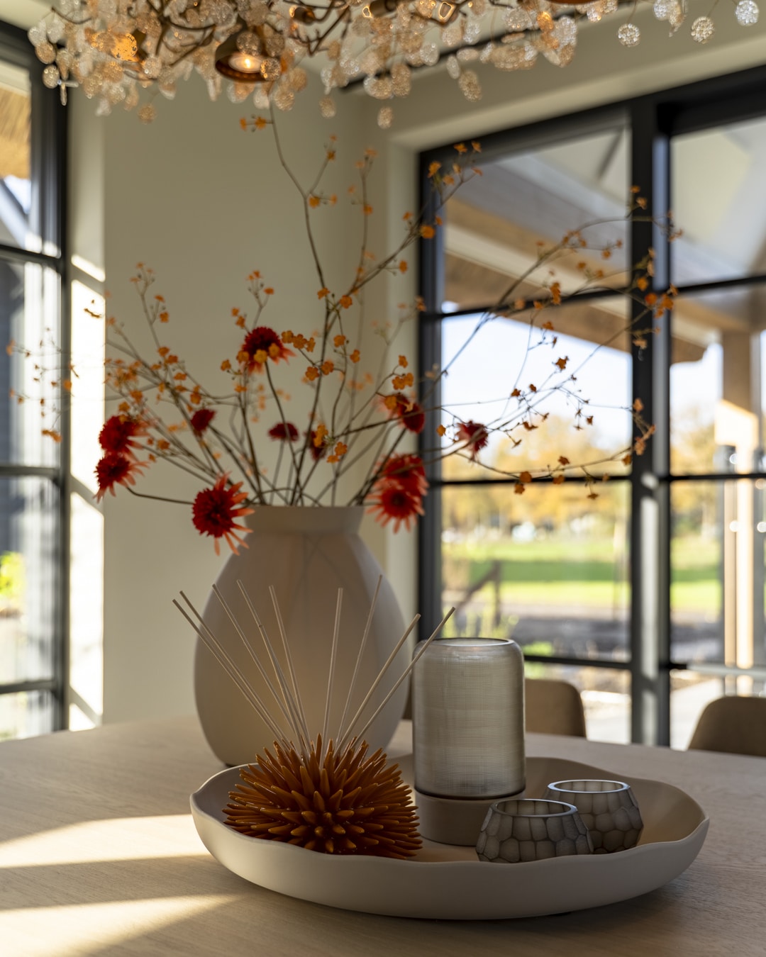 Styling van de eettafel met bloemen in warme rood- en oranjetinten.