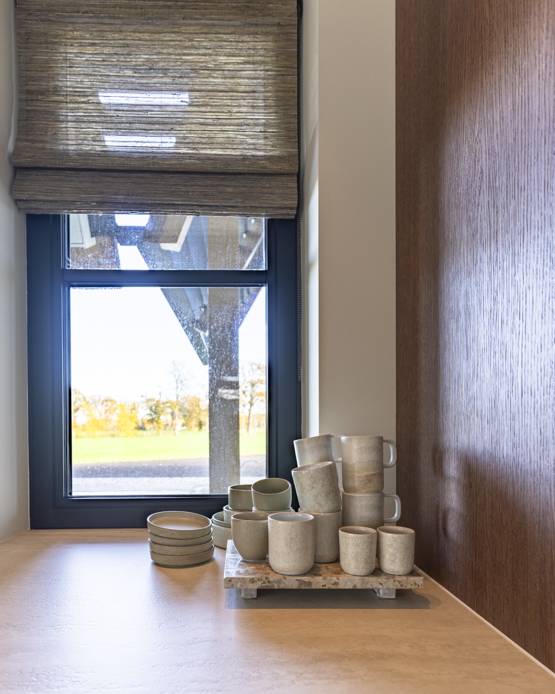 Vensterbankstyling met keramische accessoires en zachte raamdecoratie in de woonkeuken.