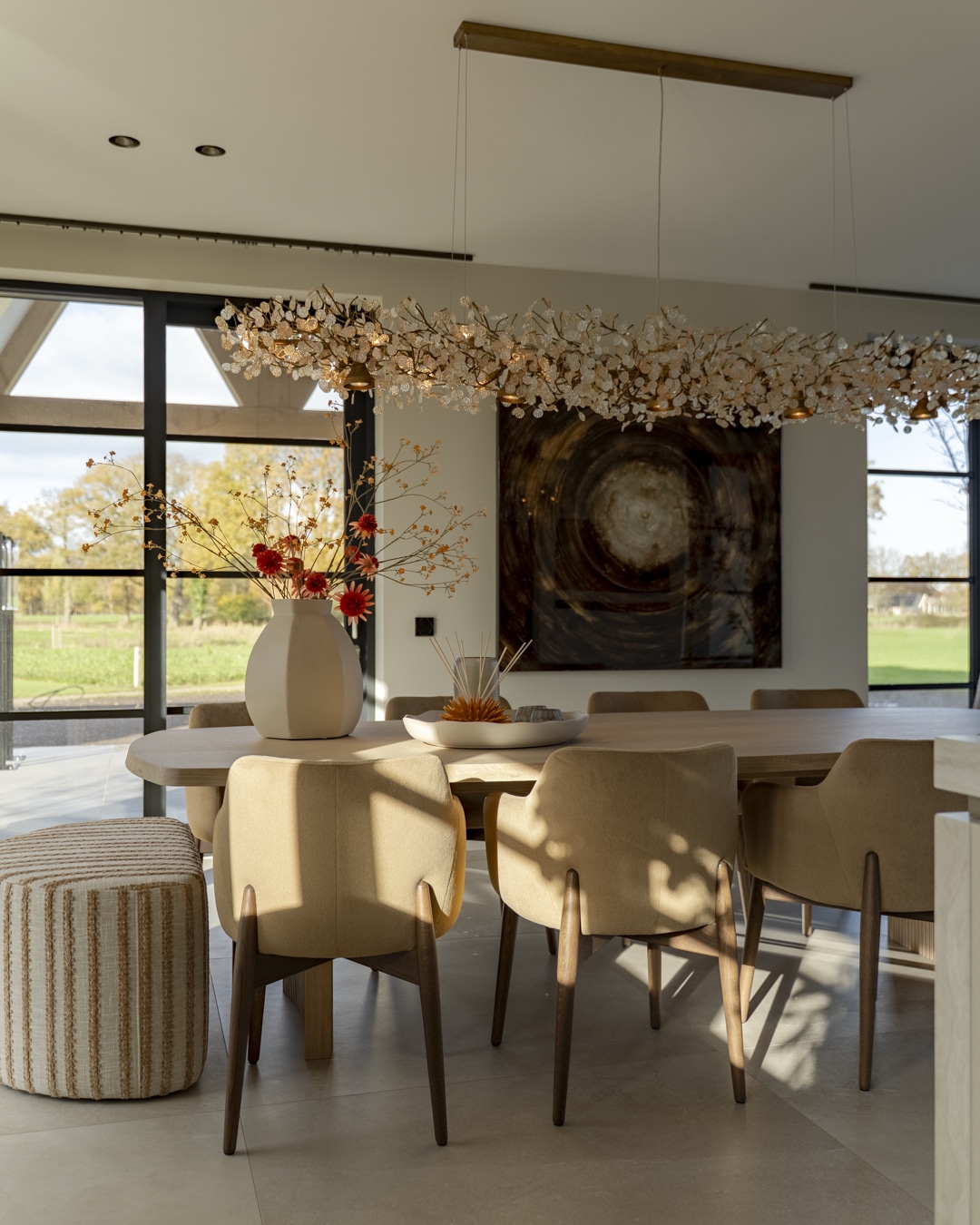 Warm ingerichte woonkeuken van nieuwbouwvilla met ovale eettafel en designverlichting.